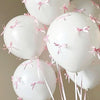 A cluster of white latex balloons tied with pink ribbons.