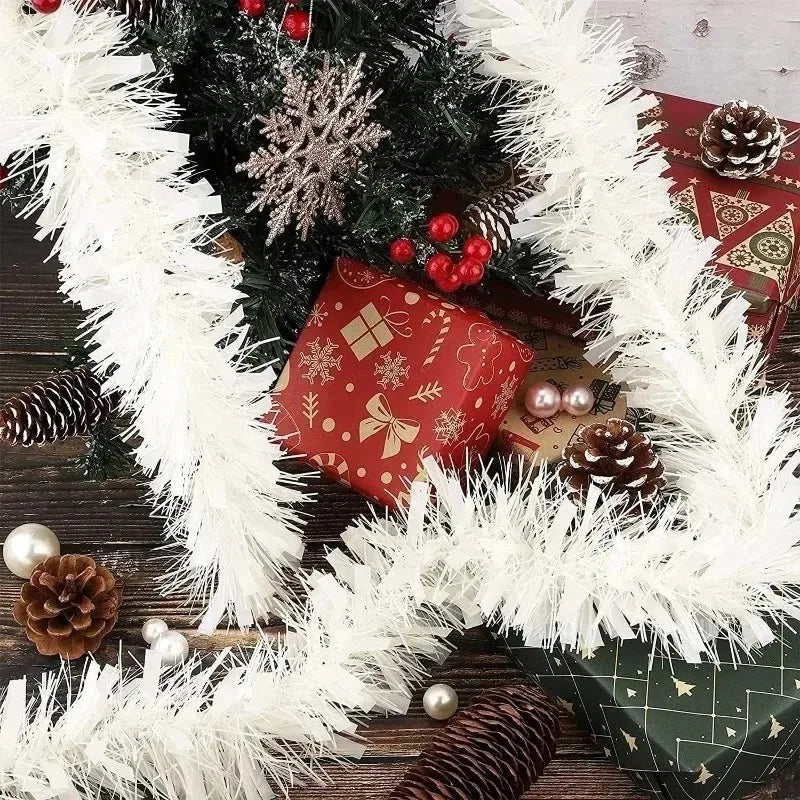 A festive holiday decoration featuring a white tinsel ribbon garland wrapped around a green fir branch with red berries and p