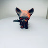 An orange and black articulated 3D printed figurine of a Siamese cat with intense red eyes.