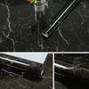 A silver metal rod with a marble finish is displayed on a black marble surface next to a glass jar of flowers.