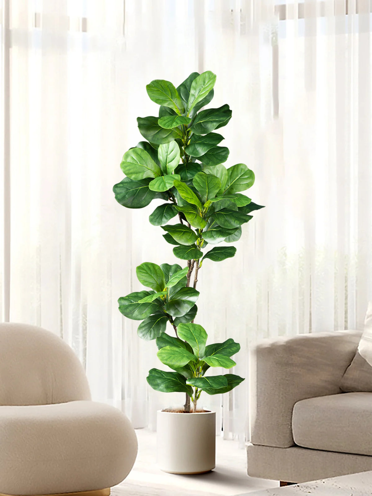 A large artificial ficus tree with green fiddle leaves placed in a white pot indoors.