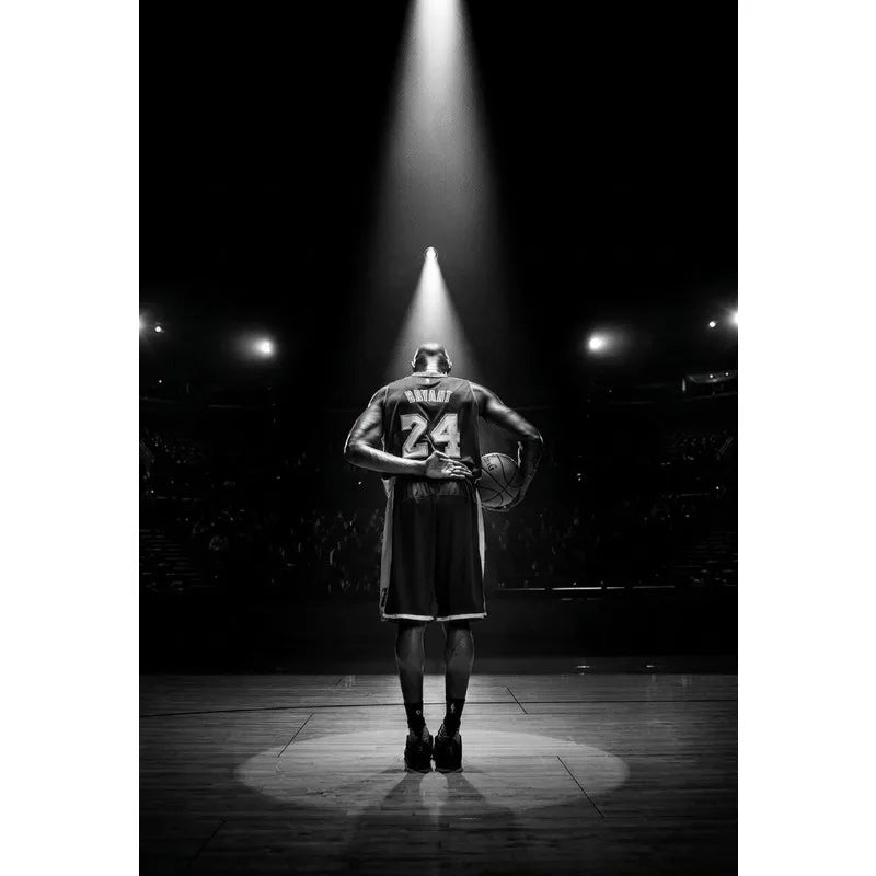 A silhouette of a basketball player stands on a court under a bright spotlight in a dark arena.