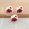 A set of festive Christmas resin decor featuring small, white, snow-covered houses with red roofs and windows.