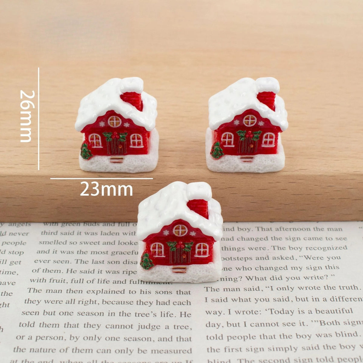 A set of festive Christmas resin decor featuring small, white, snow-covered houses with red roofs and windows.