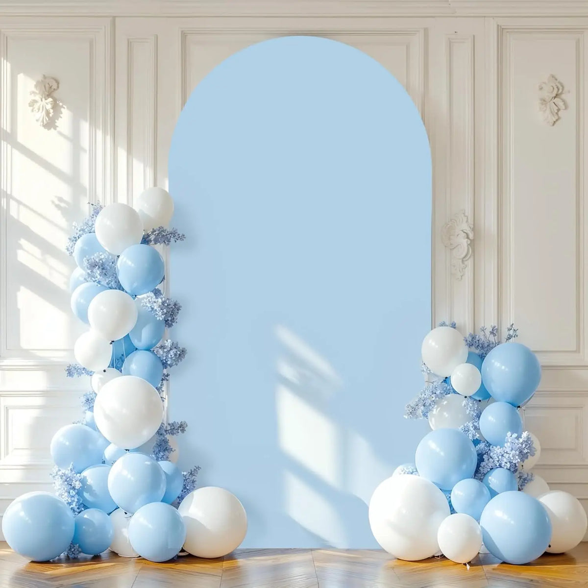 A light blue arched backdrop decorated with white and light blue balloons and silver glitter