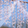 Pink sakura flower garland made of sheer white fabric hanging outdoors against a blue sky.