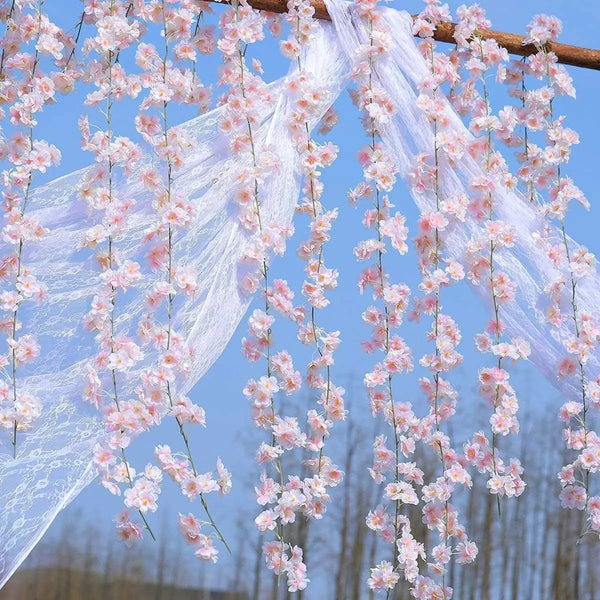 Pink sakura flower garland made of sheer white fabric hanging outdoors against a blue sky.