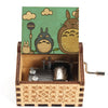 A hand-cranked wooden music box featuring a Totoro design on the lid and intricate wood carving on the base.