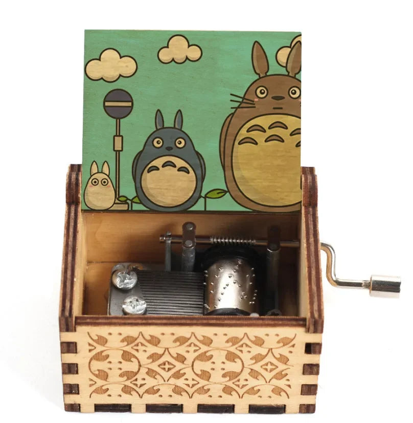 A hand-cranked wooden music box featuring a Totoro design on the lid and intricate wood carving on the base.