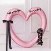 Pink heart-shaped balloon decoration with Happy and Birthday text on it