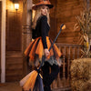 A woman dressed as a witch with an orange and black costume, including a pointed hat, tulle skirt, and broomstick, standing o