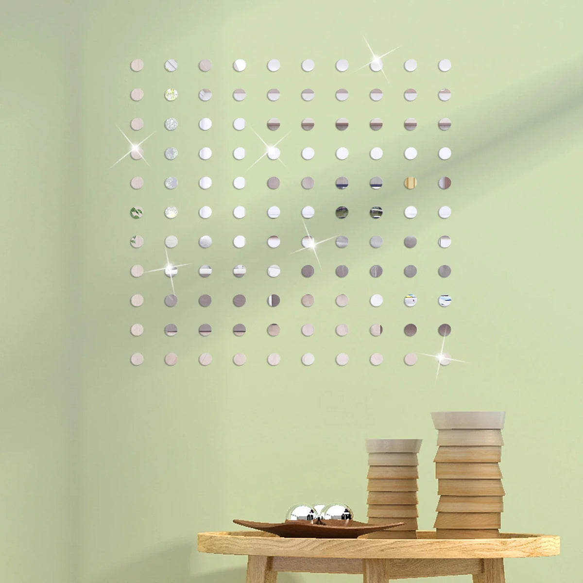 A grid of round mosaic mirror decals in various shades of silver and gray mounted on a light green wall.