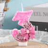 Pink glitter birthday candle shaped like the number 3 with a pink bow