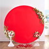 A large, round red photo backdrop decorated with floral greenery and scattered red petals.