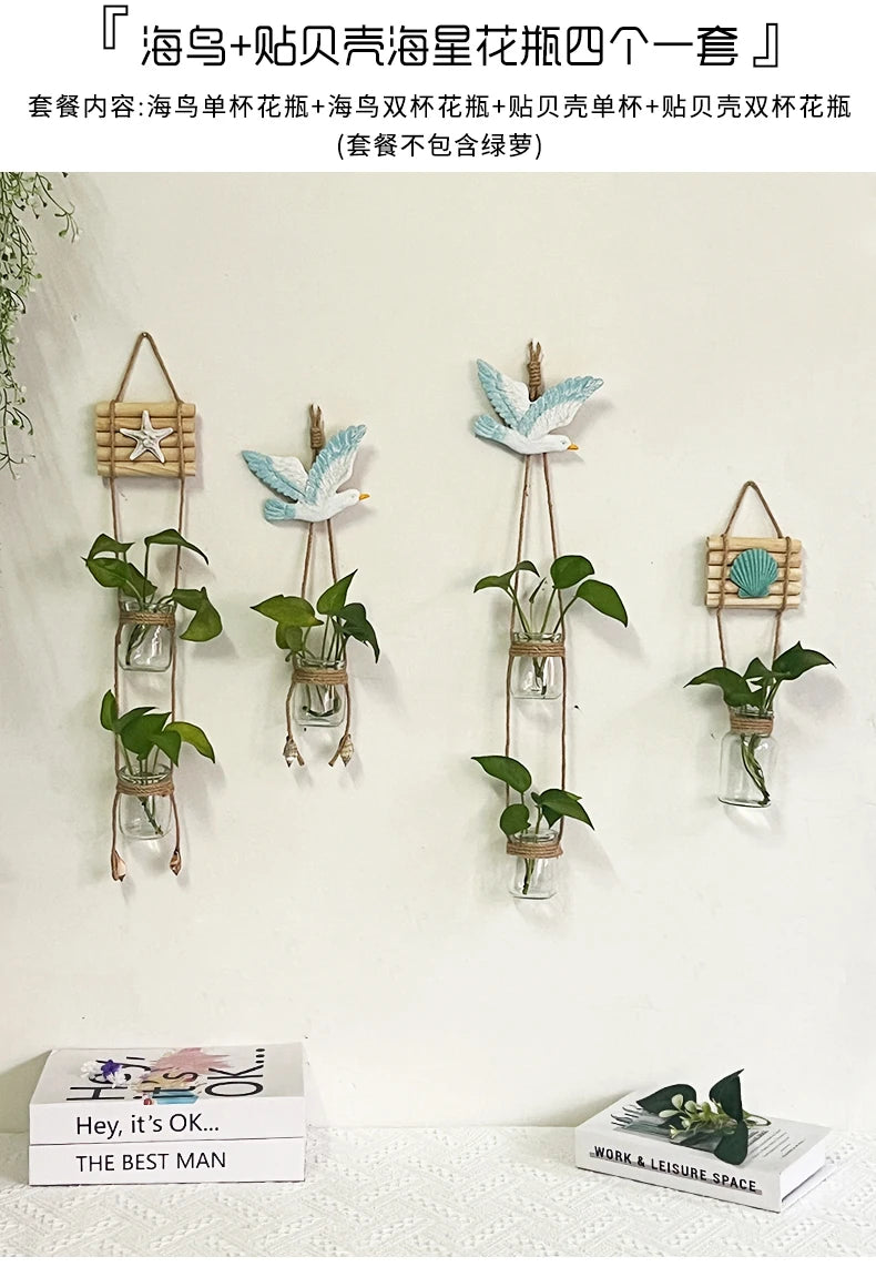A collection of decorative glass terrariums featuring various indoor plants and floral elements hanging on a white wall.