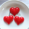 A set of three glossy red heart-shaped fridge magnets displayed on a white plate.