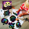 A child is creating Halloween scratch art cards on paper, surrounded by finished designs and a box.