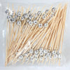 A bundle of bamboo fruit skewers with silver-colored spherical tops packaged in clear plastic.