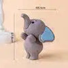 A small gray elephant cake topper with light blue ears, displayed on a light background.