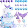 A tiered mermaid cake decorated with purple and blue accents, featuring various sea creature toppers and seashells.