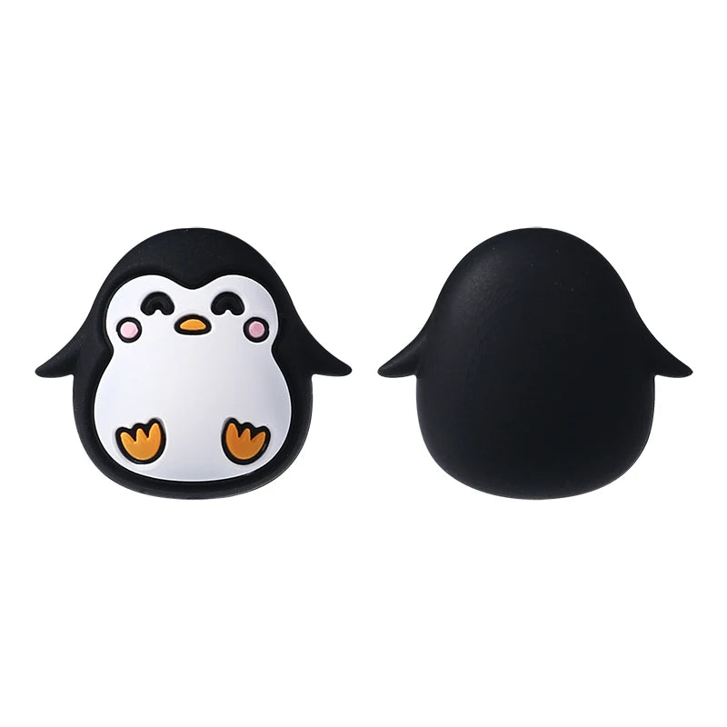 A pair of black silicone plant beads shaped like an owl with white facial features and orange feet.
