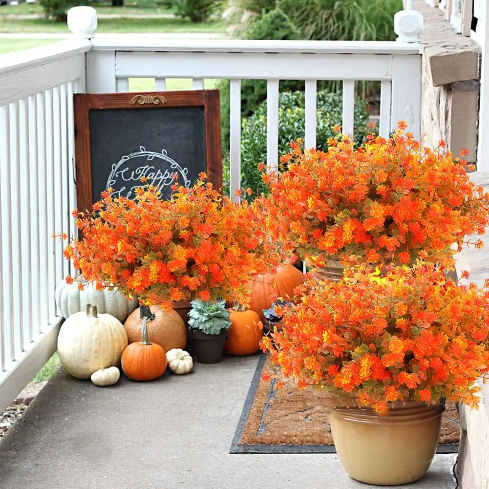 An orange artificial flower hanging basket with autumn gourds sits on a porch railing.