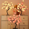 Schwarzer Ast mit leuchtend rosa und weißen Rosenblüten und einem kleinen rosa Flamingo