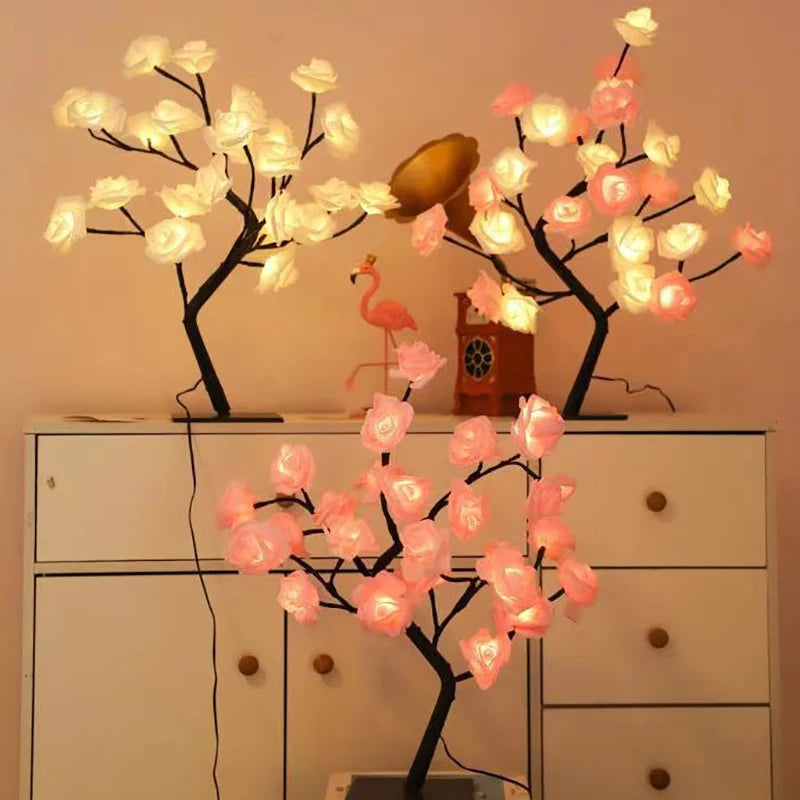 Schwarzer Ast mit leuchtend rosa und weißen Rosenblüten und einem kleinen rosa Flamingo