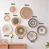 A collection of woven straw wall hangings in various sizes and textures, displayed against a white wall.
