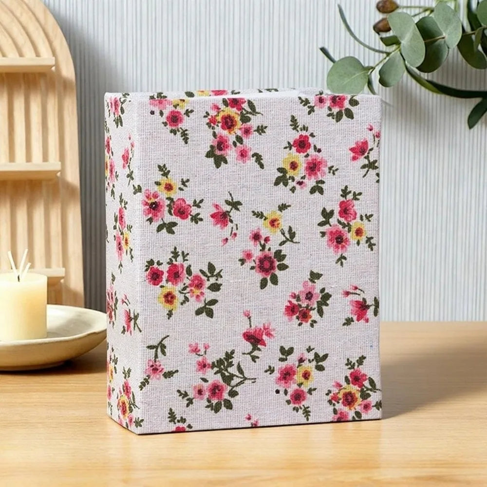 Quadern-Linen-Album mit rosa-gelbem Blumenmuster auf Holzoberfläche.