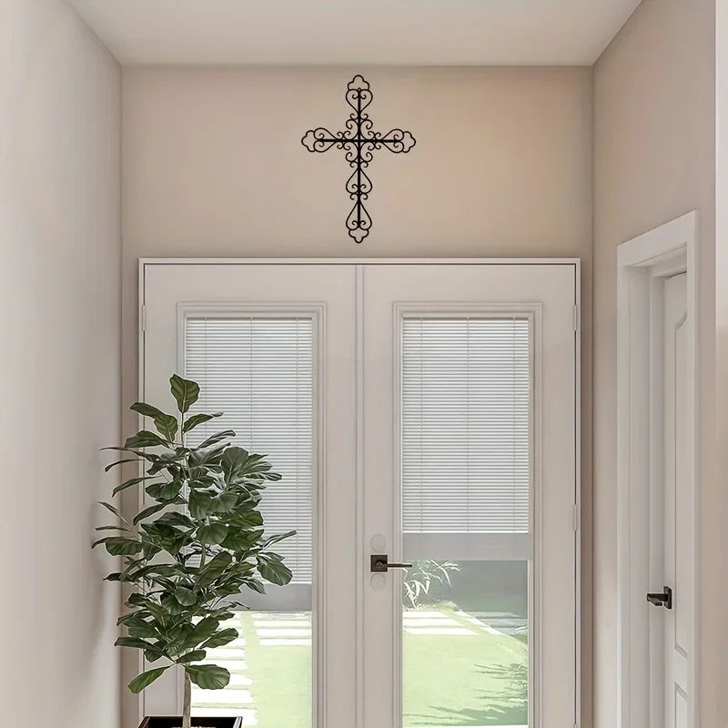 Art Deco metal cross wall decor mounted on a light beige wall above a pair of glass doors.