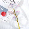 A delicate branch of rainbow artificial crystal flowers with iridescent petals on a gold stem.