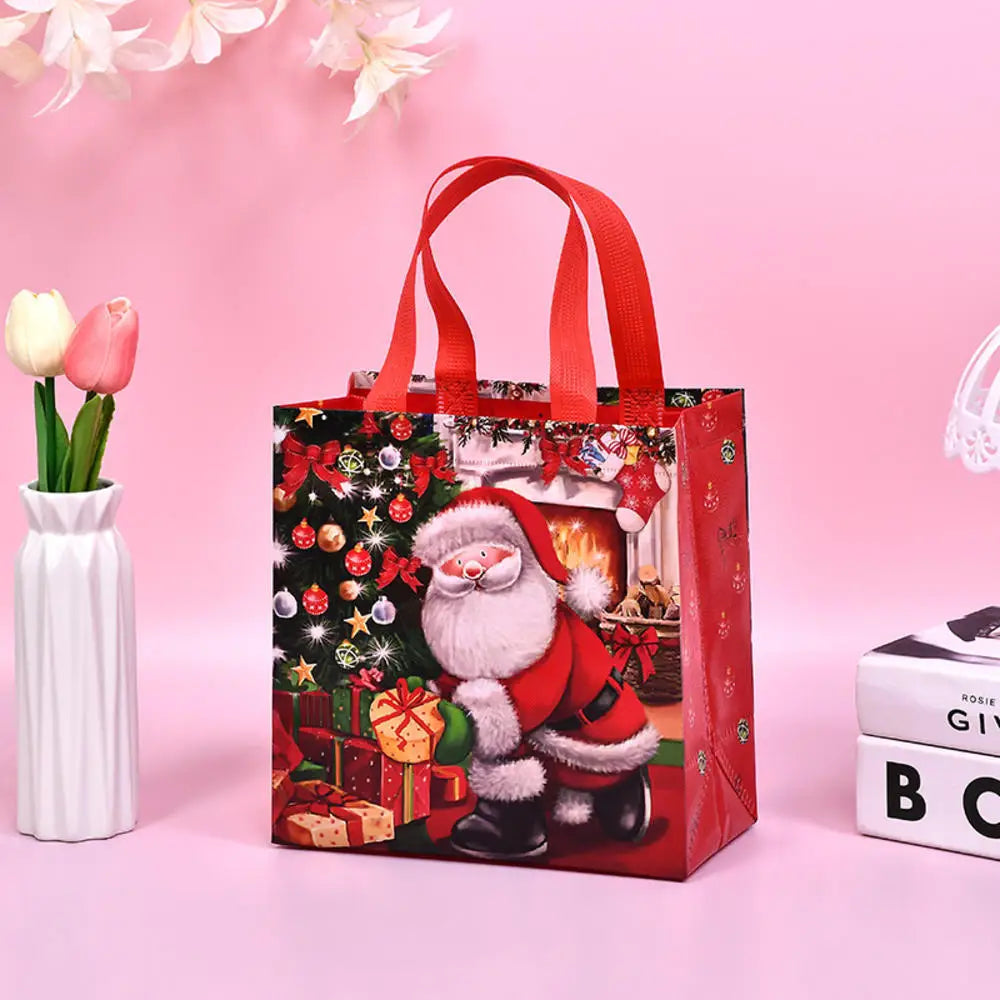 A red non-woven gift tote bag featuring a festive Christmas print with Santa and gifts, set against a pink background.
