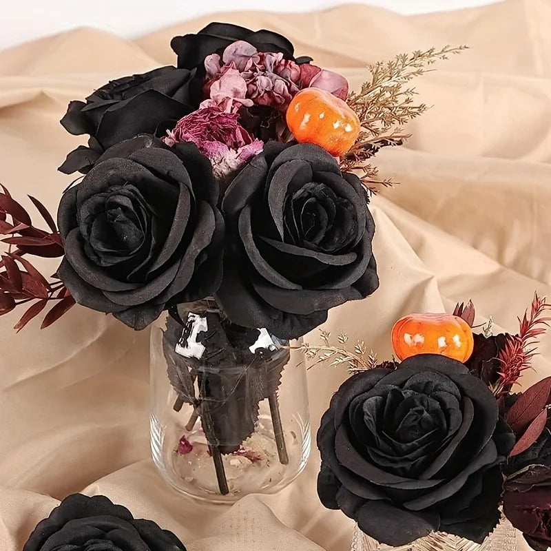 A bouquet of artificial black roses and dried floral elements displayed on a light fabric background.