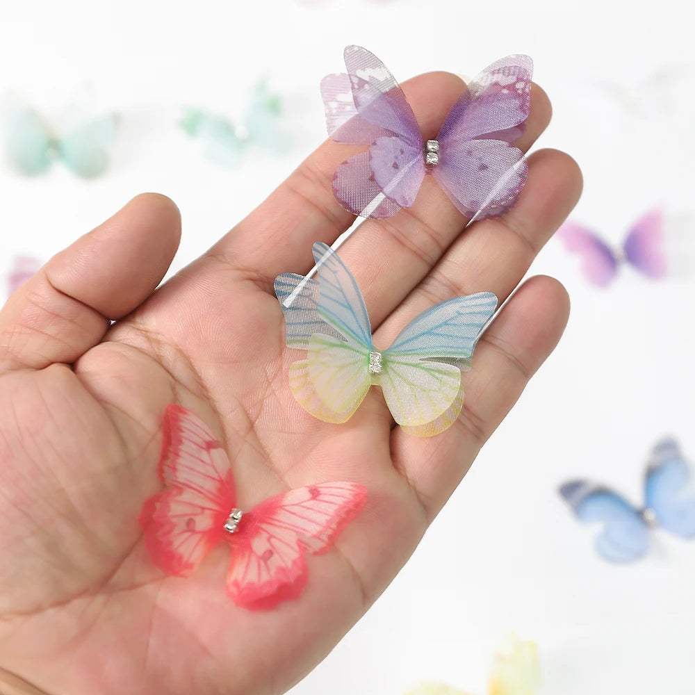 A hand holds several 3D embroidered butterfly patches in shades of purple, blue, and pink for crafts and decor.