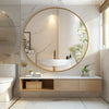 A large round vanity mirror with a matte metal frame above a white vessel sink in a modern bathroom.