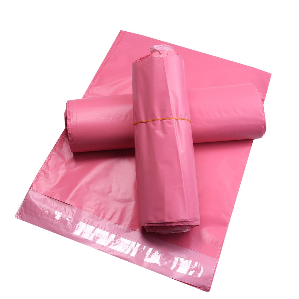 A roll of pink plastic self-adhesive shipping pouches is displayed on a pink sheet.