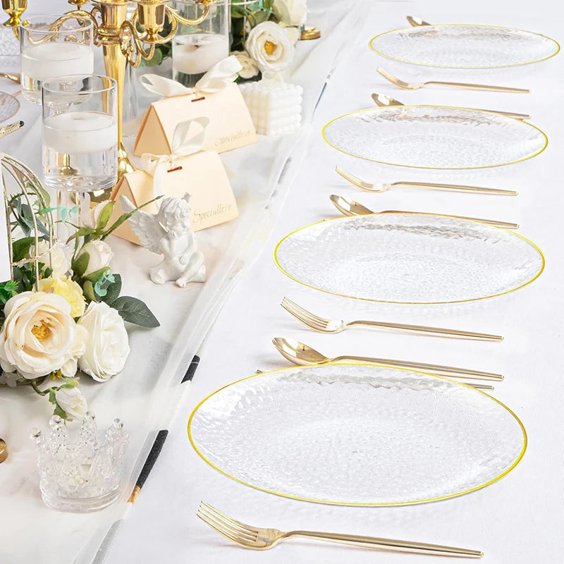A set of hammered gold rim disposable dinner plates, silverware, and candle holders arranged on a white surface.