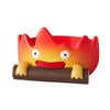 A resin cartoon fire person tray with an orange and red face emerging from a brown base.