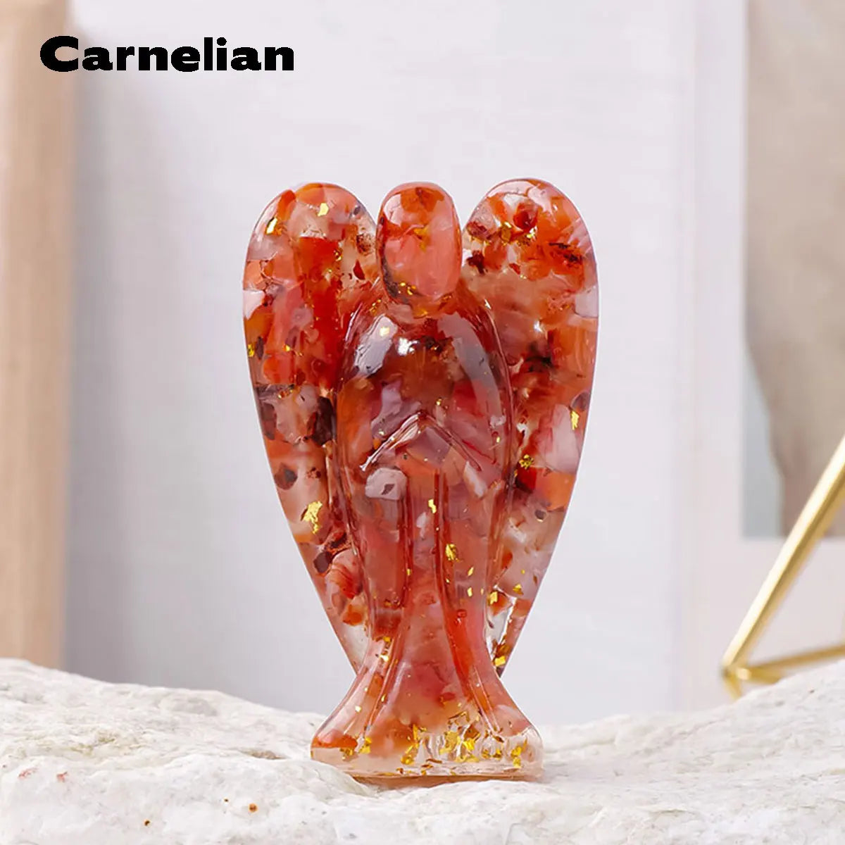 A translucent reddish-orange crystal figurine shaped like a guardian angel, resting on a light surface.