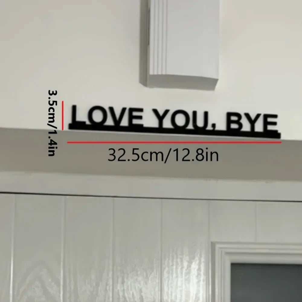 Black metal wall art sculpture with the text LOVE YOU BYE mounted on a white wall.