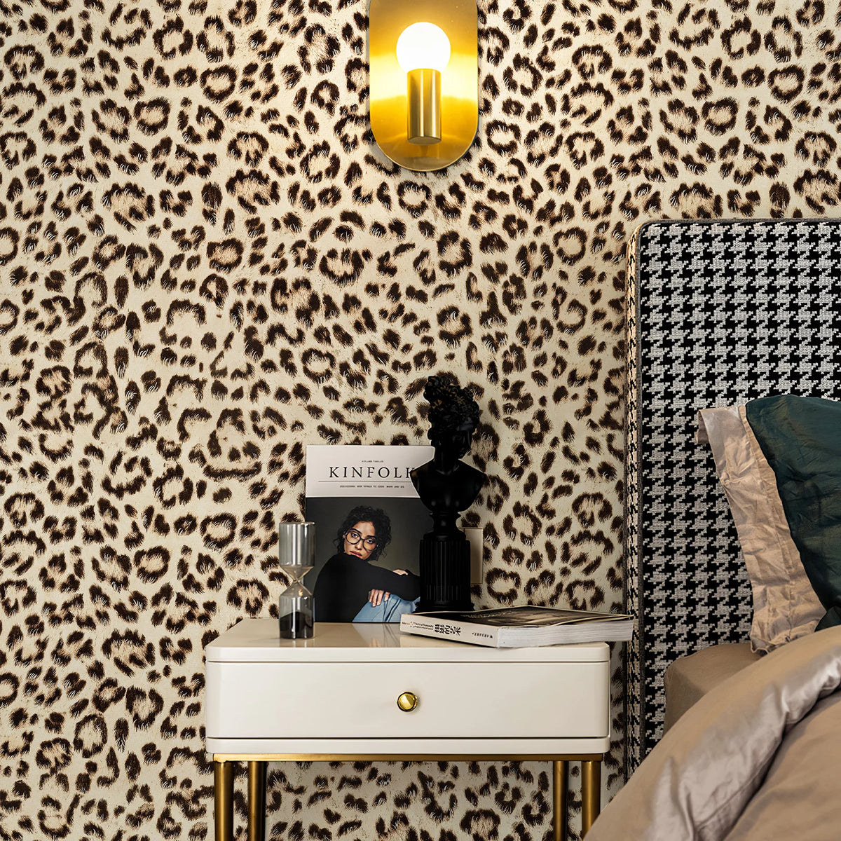 A close-up of a room decorated with retro leopard print wallpaper and a gold lamp above a nightstand.
