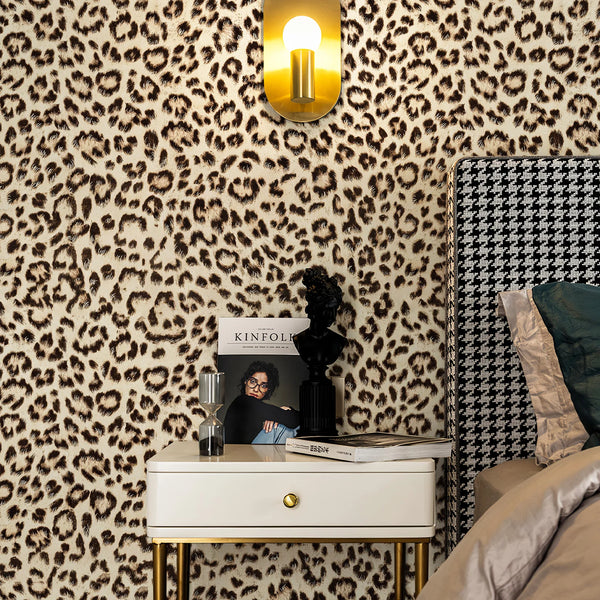 A close-up of a room decorated with retro leopard print wallpaper and a gold lamp above a nightstand.