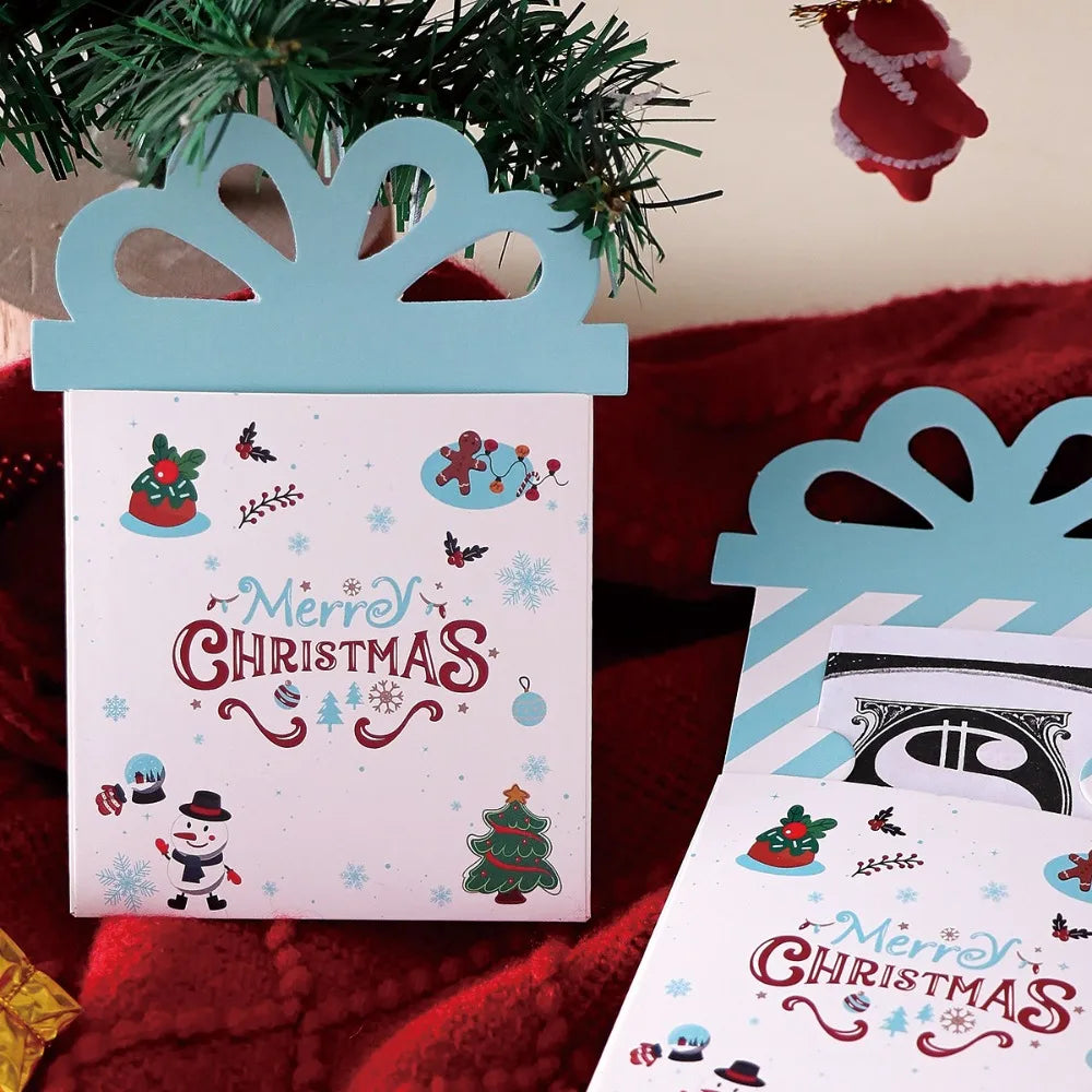 A set of three pink and blue cartoon Christmas thank you cards with festive designs displayed on a red fabric.