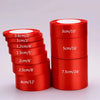 A collection of red satin ribbon rolls in various widths and lengths displayed next to a large roll.
