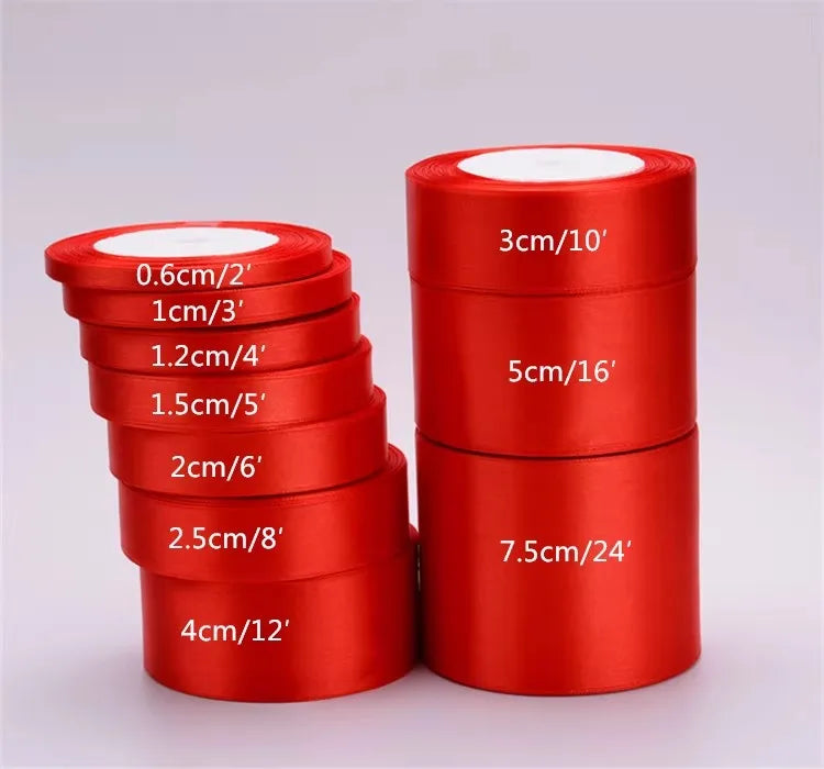 A collection of red satin ribbon rolls in various widths and lengths displayed next to a large roll.