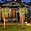 An artificial golden palm tree stands in a lawn next to a house at dusk, illuminated by string lights.