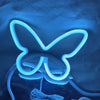 A glowing blue neon sign shaped like a butterfly is displayed against a dark blue fabric background.