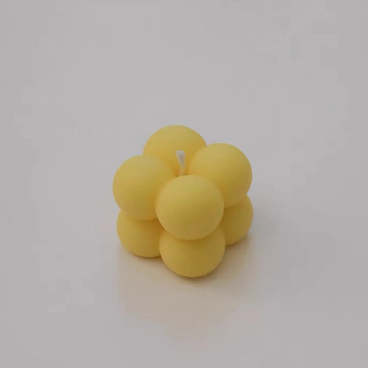 A cluster of yellow soy wax candles, some white and pink, arranged together.
