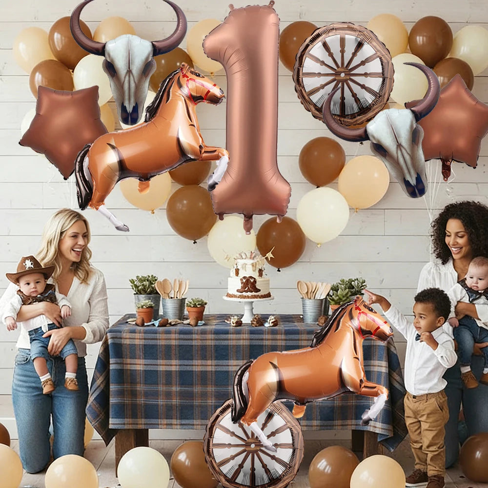 A collection of brown and gold foil balloons shaped like horses and the number one set against a white wooden background.